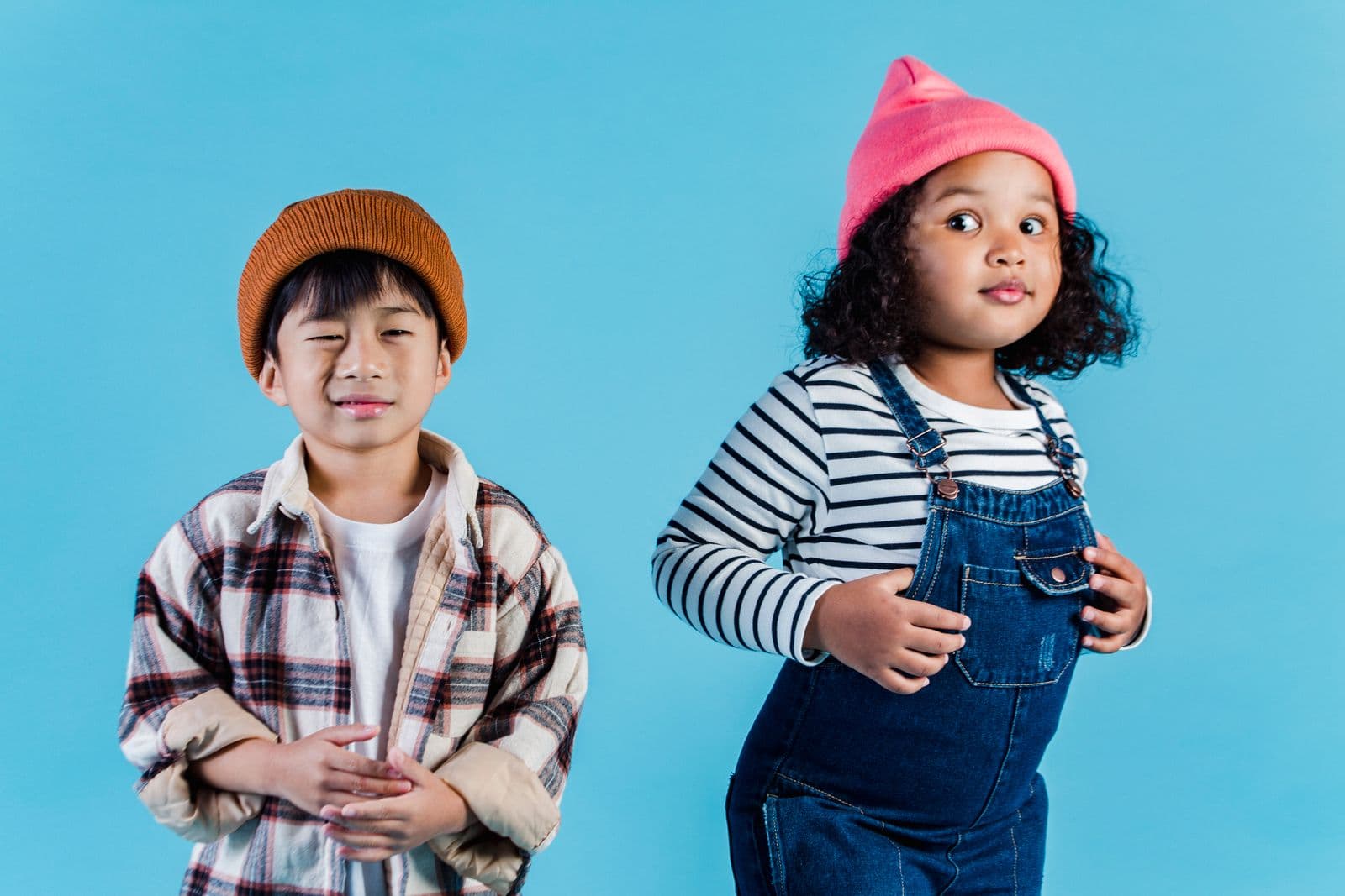 Two happy kids in colorful outfits and beanies